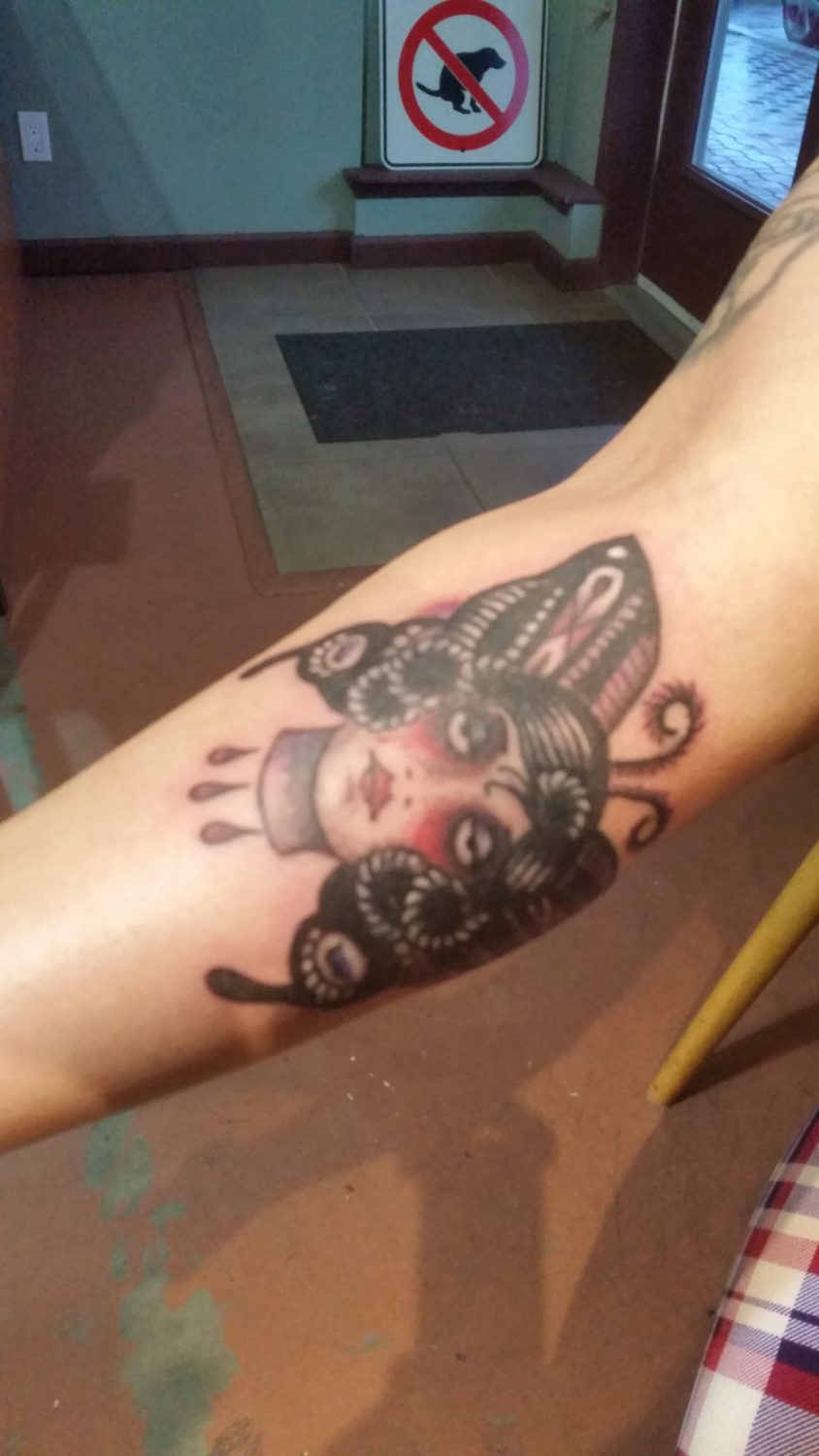 Small colour butterfly and portrait tattoo on an arm