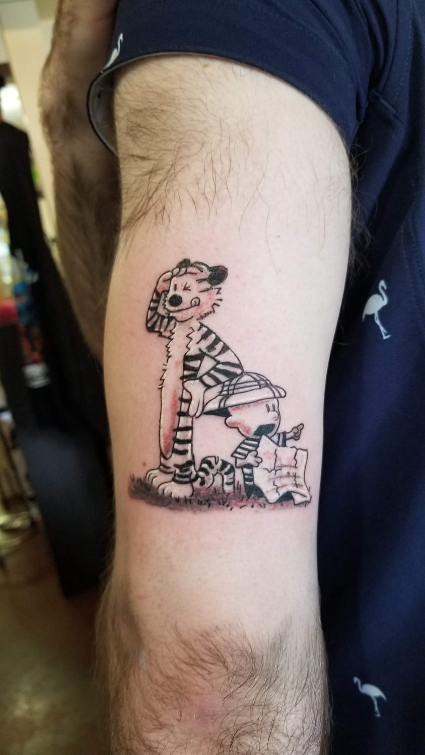Black and grey Calvin and Hobbes cartoon tattoo on an upper arm, Parksville BC