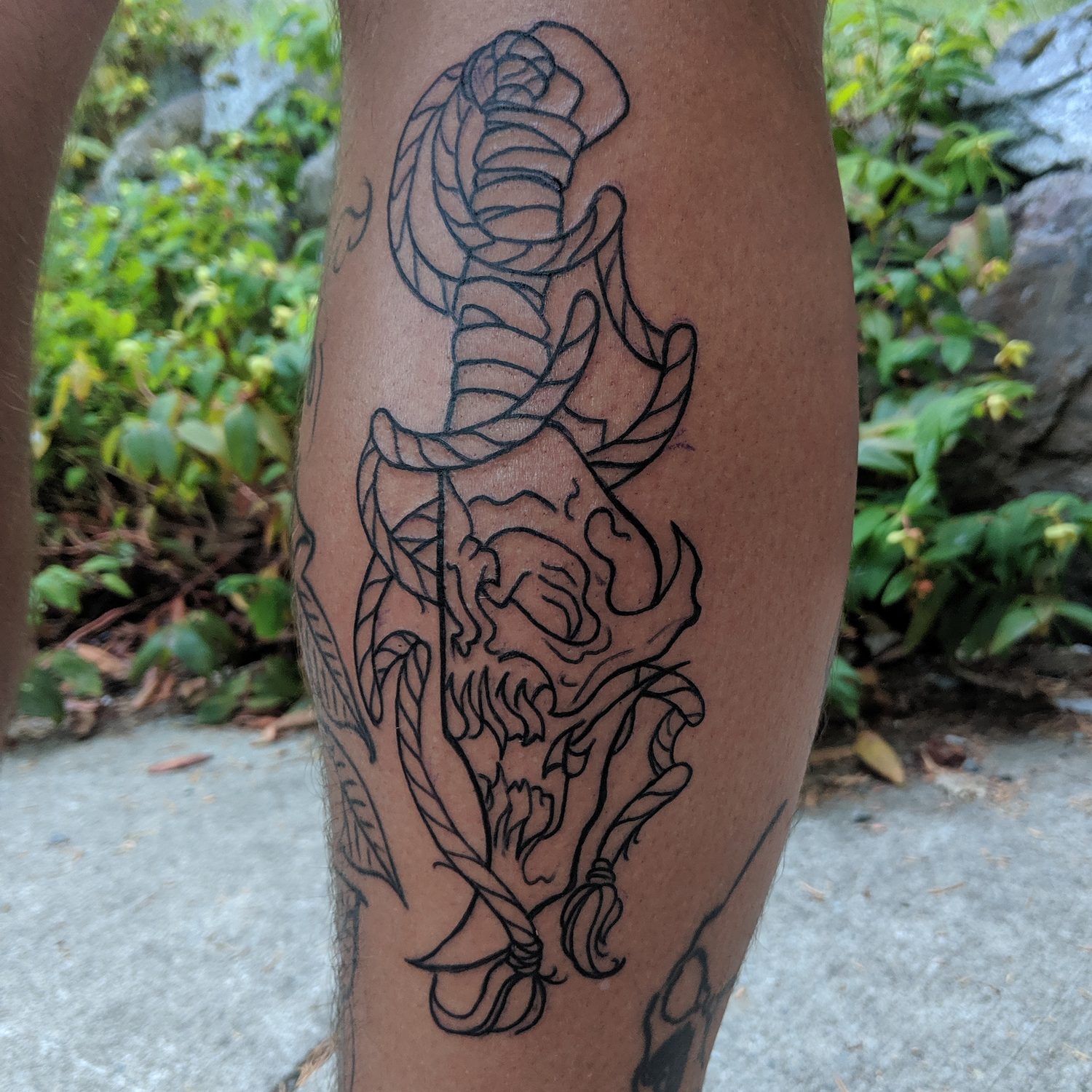 Black linework dagger, snake and skull tattoo on a calf, Vancouver Island