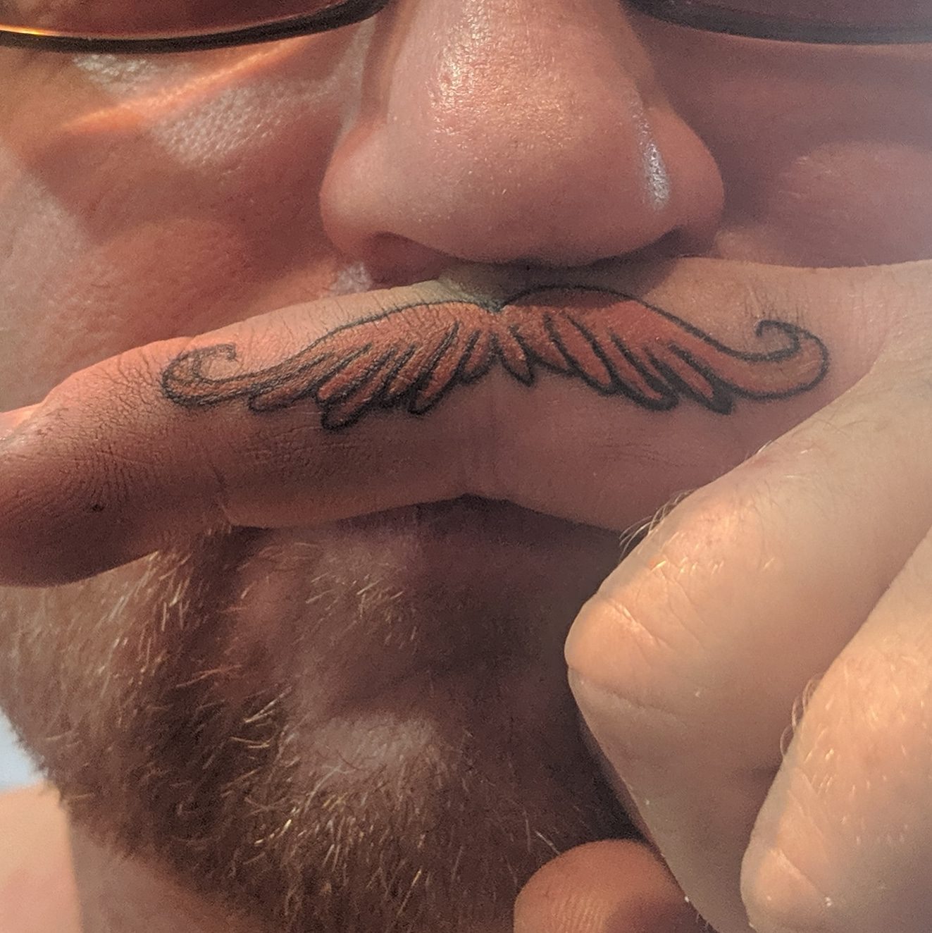 Handlebar moustache tattooed on the side of a finger, a novelty finger-stache, Parksville BC