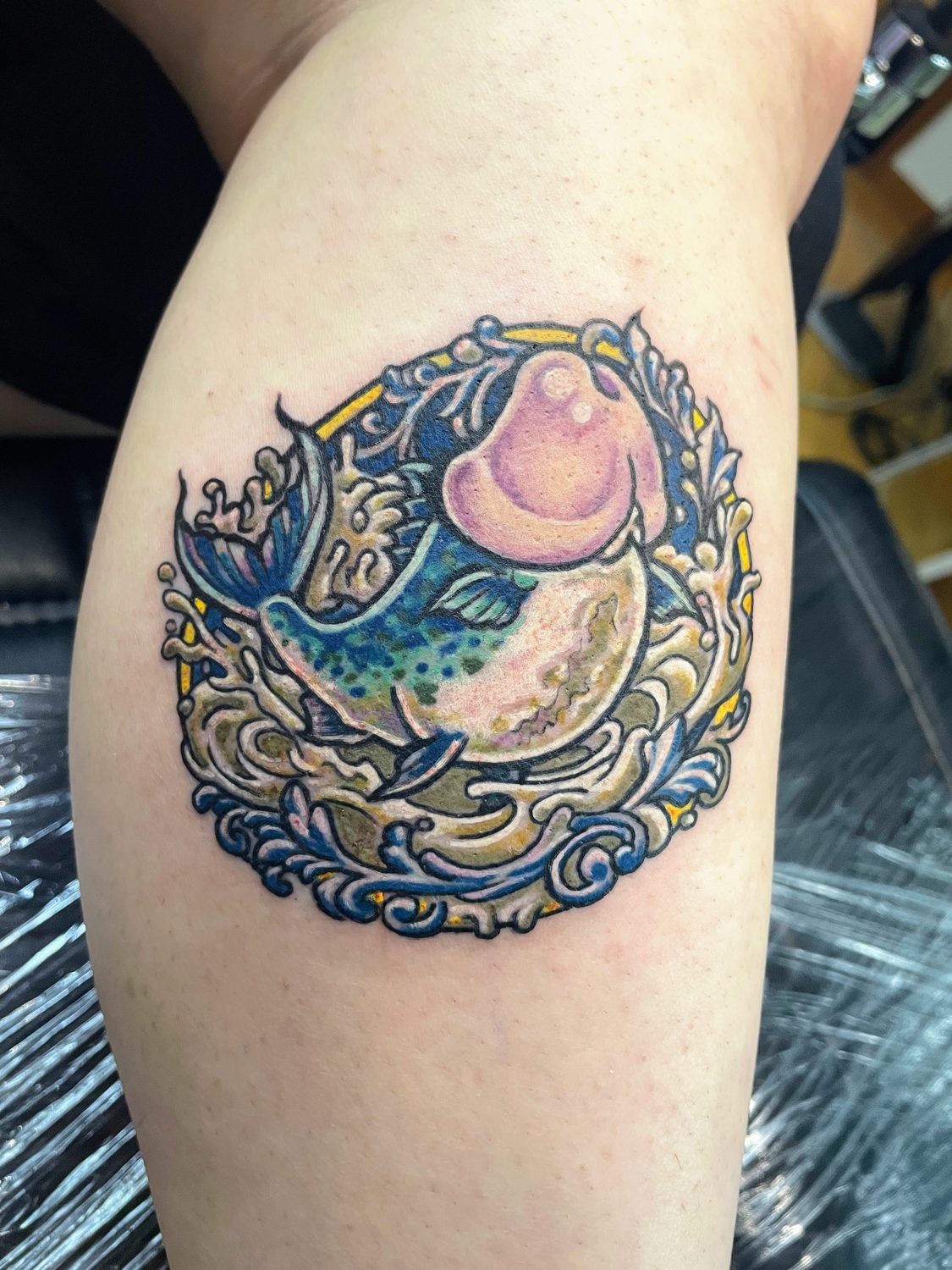 Colour Japanese-style leaping fish framed by waves, leg tattoo, Vancouver Island