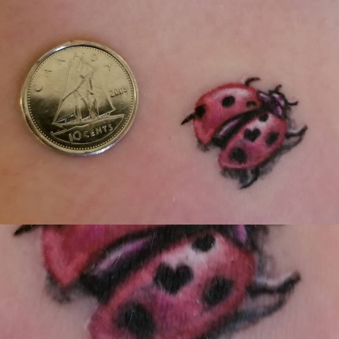 Tiny colour ladybug micro-tattoo shown next to a dime for scale, Vancouver Island
