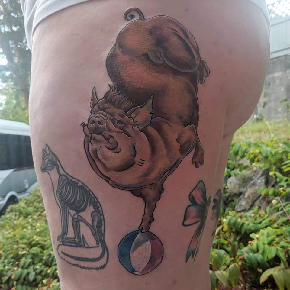 Colour pig balancing on a beach ball, thigh tattoo, Parksville BC