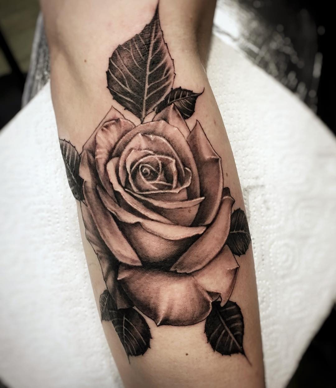 Black and grey realistic rose tattoo on a forearm