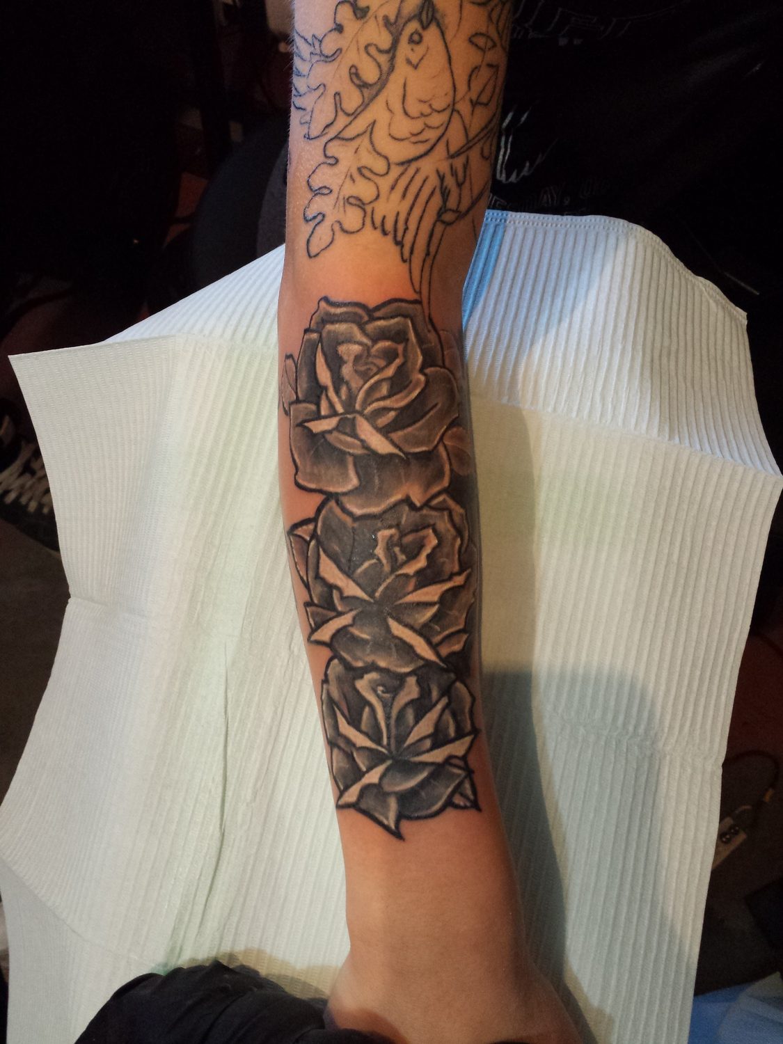 Black and grey rose sleeve cover-up over old ink, forearm, Parksville BC